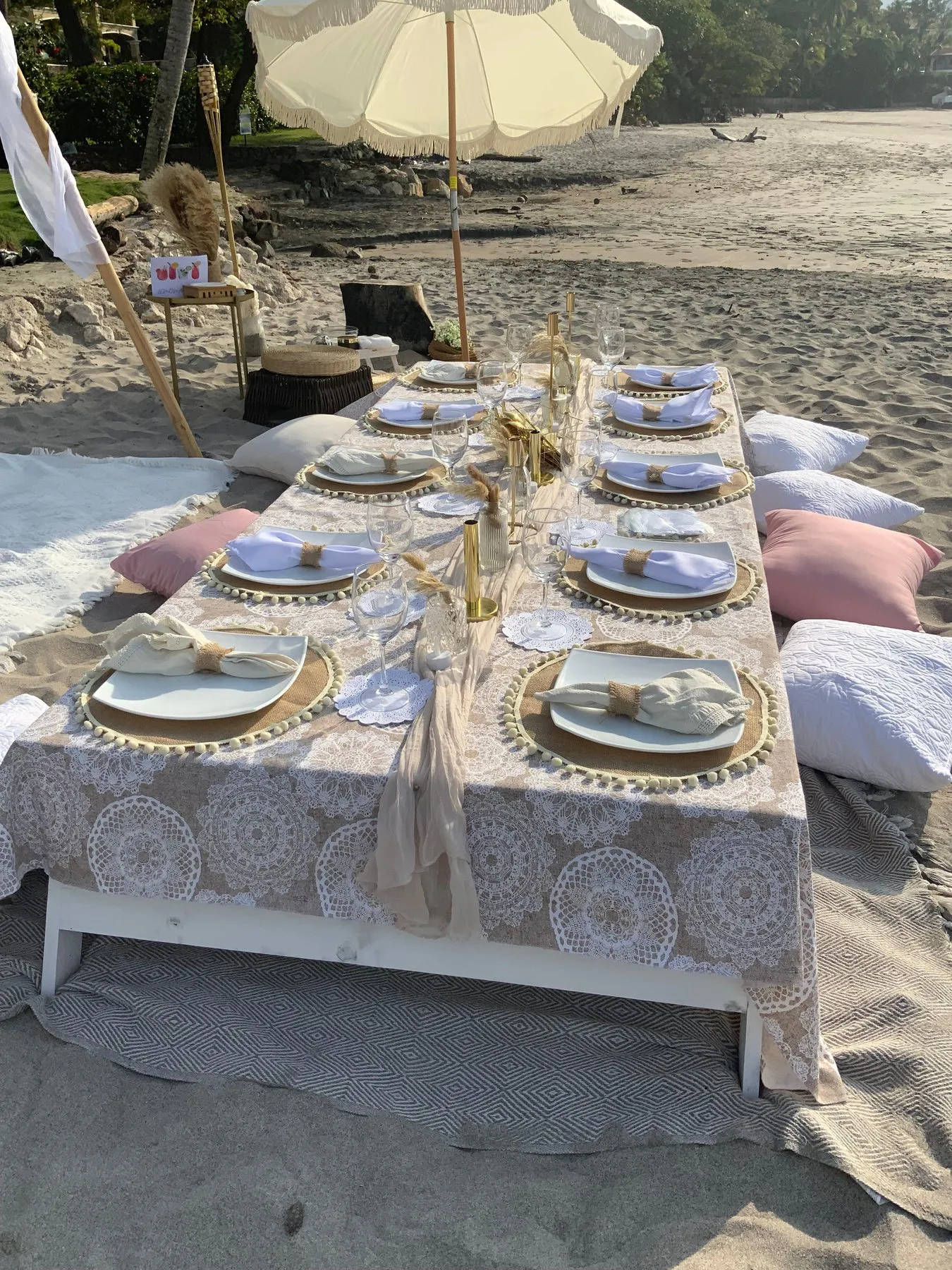 Mesa larga de picnic en la arena con platos dorados